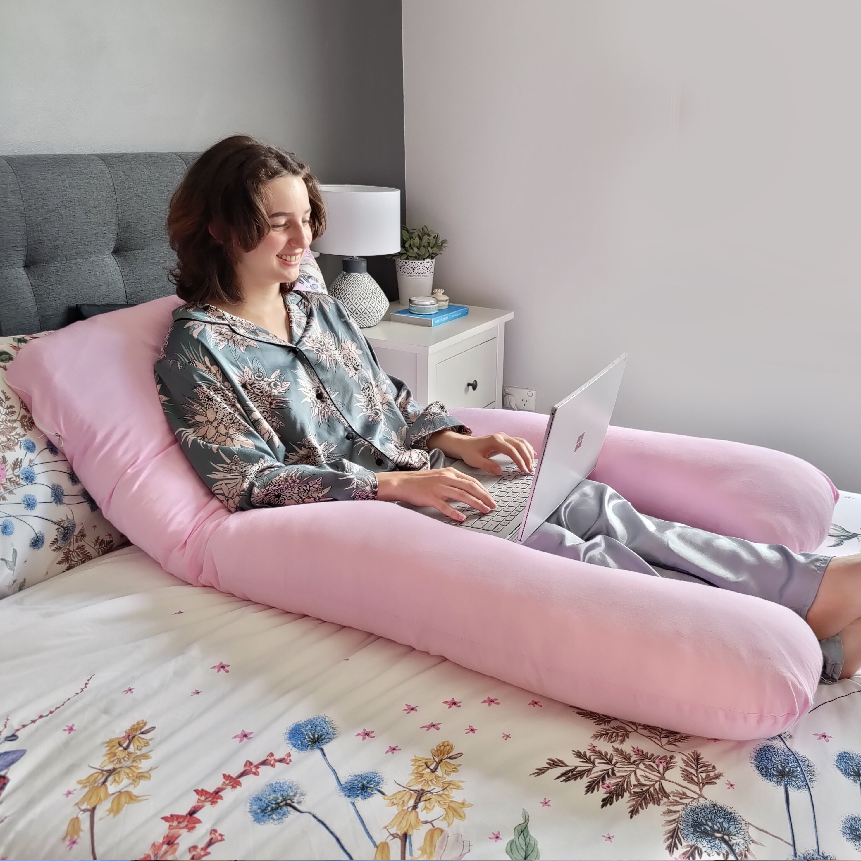 Pink Pillow Pod in Use by Girl on Laptop on Bed with Flowery Bed Spread